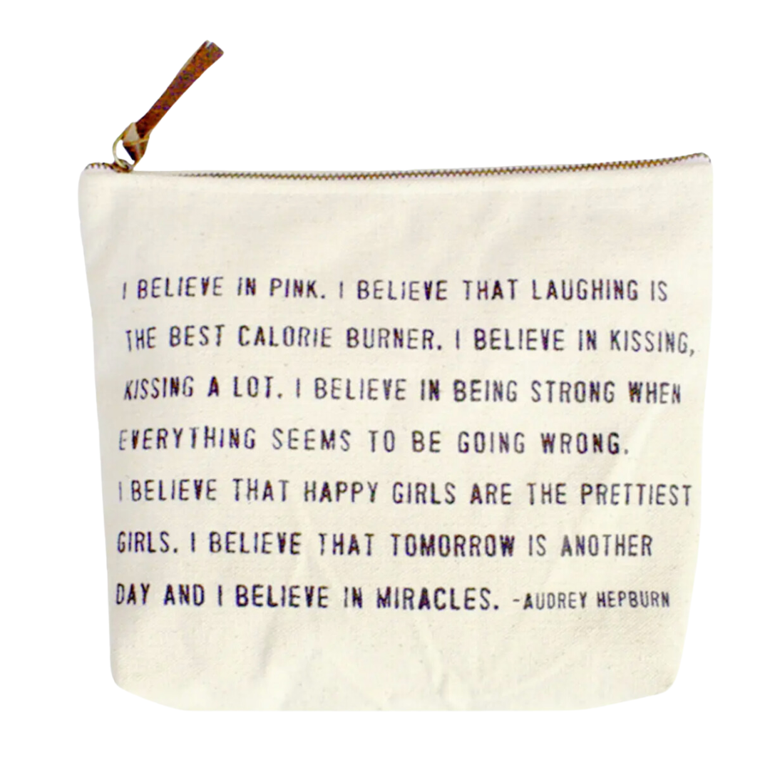 The "I Believe in Pink" canvas zip pouch displays an inspirational quote from Audrey Hepburn. The pouch is 9 x 7 inches and features a sturdy canvas material with a leather zipper tab. The quote emphasizes optimism, strength, and the belief in miracles, offering both practicality and a daily reminder of hope for those undergoing treatment.