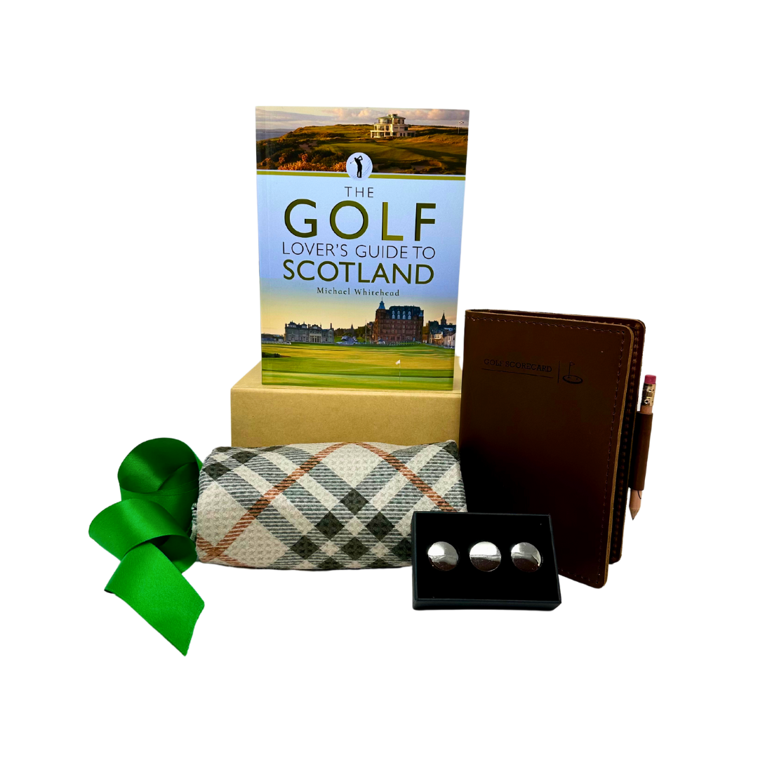 A curated gift box by Me To You Box named 'In The Zone'. It includes a leather score book with pencil, a plaid towel, golf ball markers, a flask, and a book on golf in Scotland.