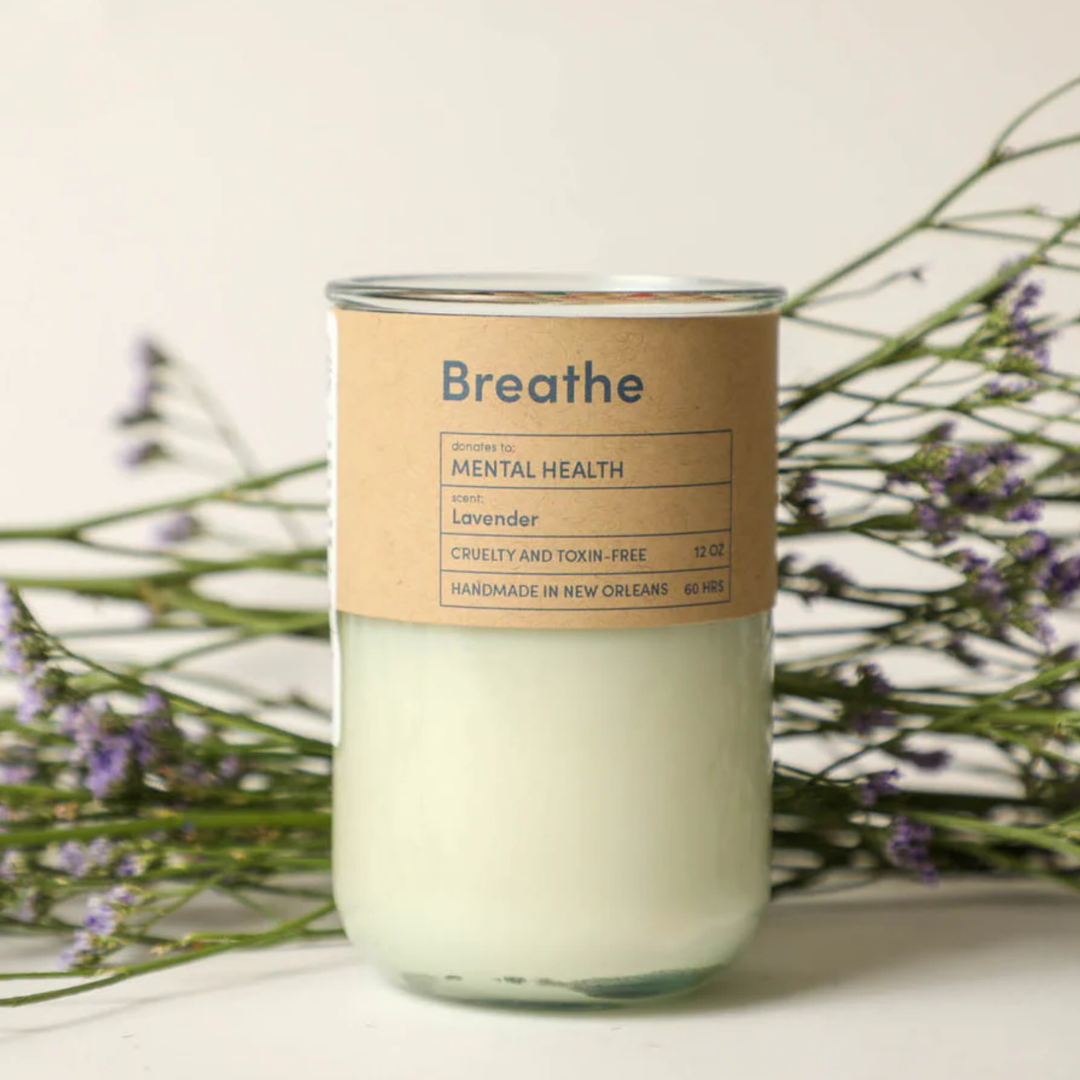 Candle with a 'Breathe' label on a light background with lavender flowers.