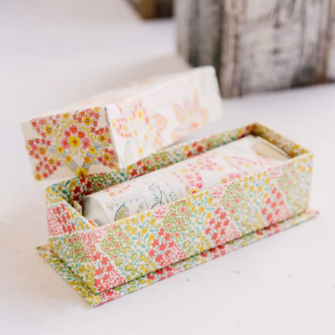 Floral-patterned box with rolled-up paper inside on a light surface