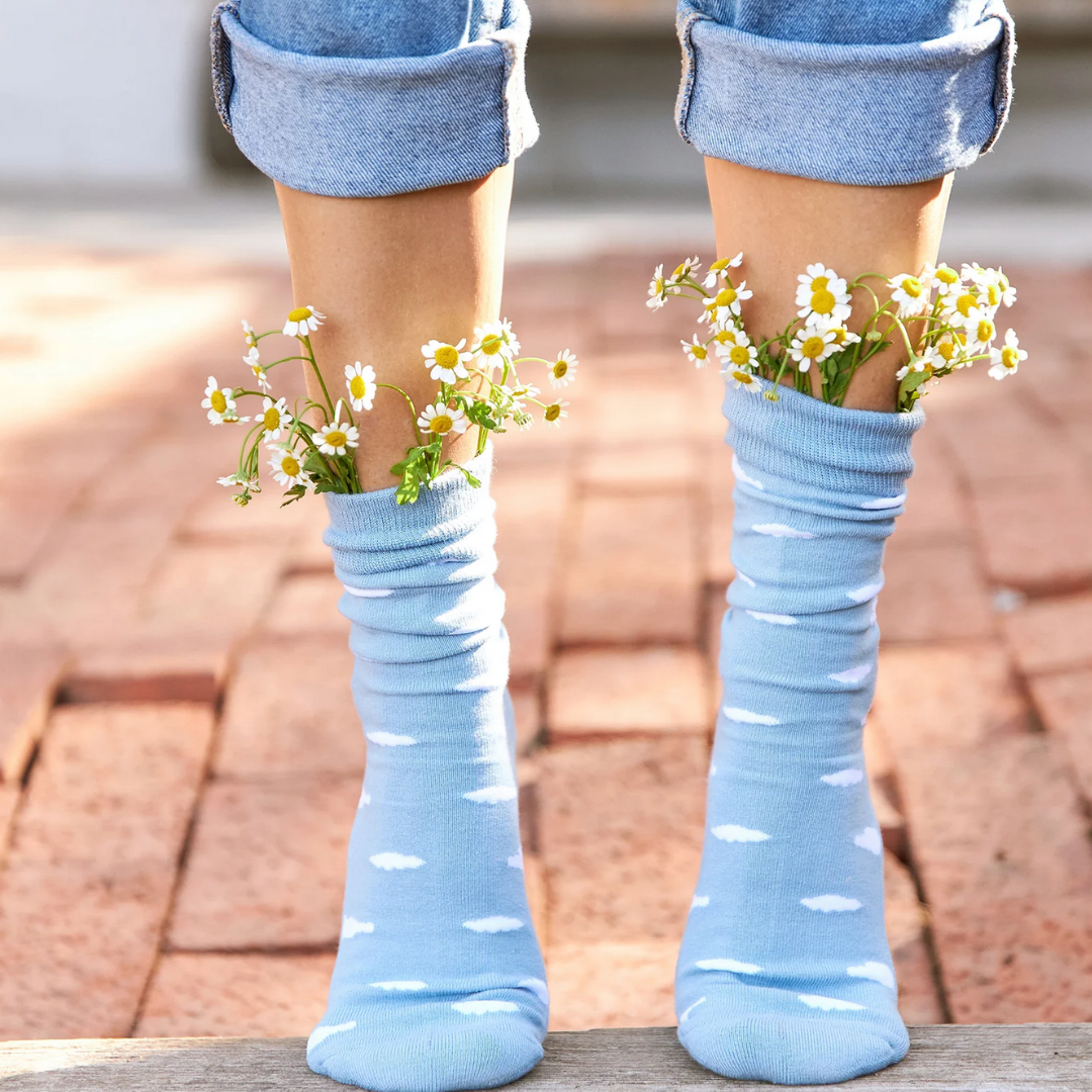 Light blue socks with white cloud pattern worn by a person on a brick outdoor background