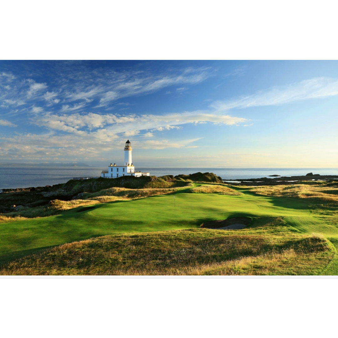 Golf course with a lighthouse on a cliff overlooking the ocean under a blue sky.