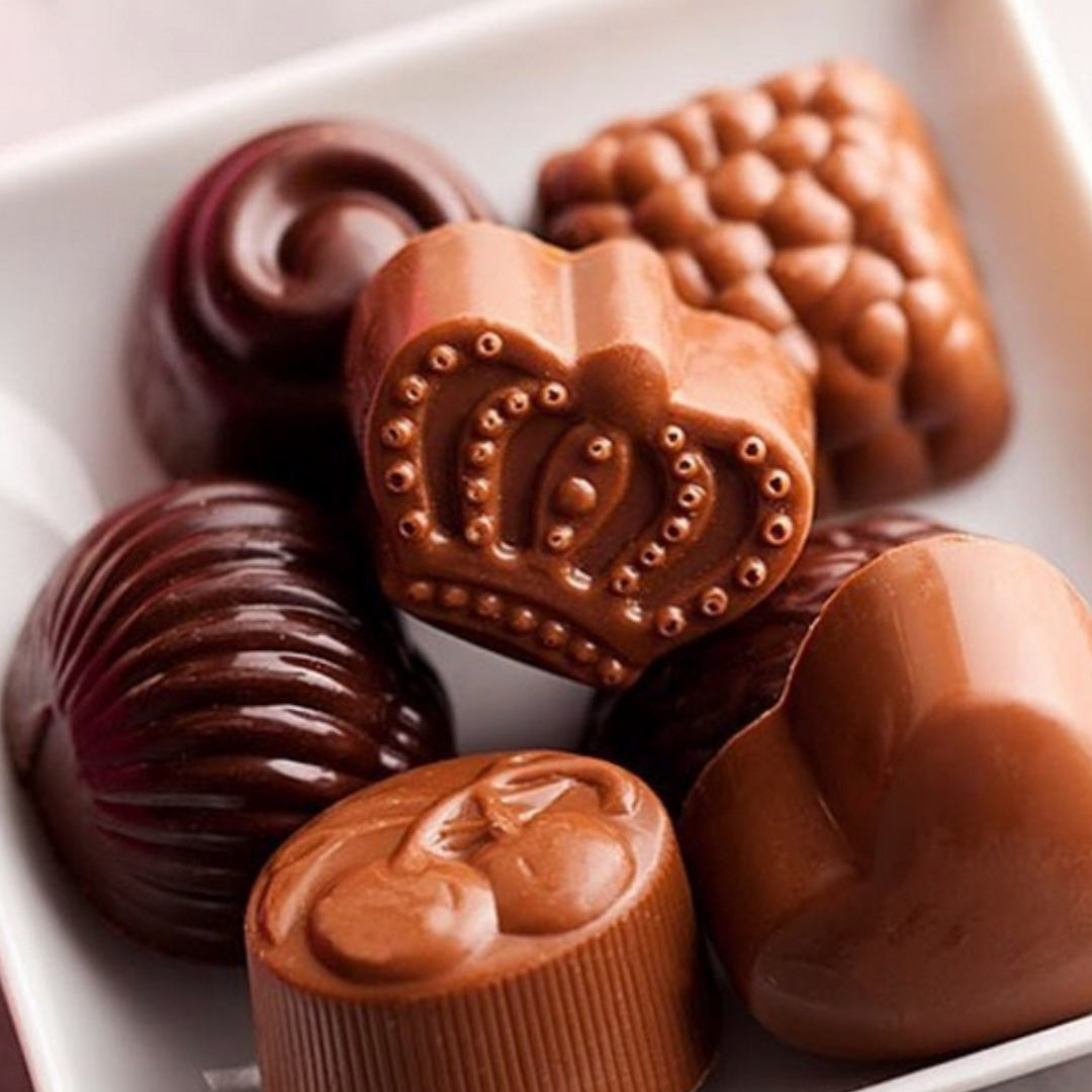 Louis Sherry chocolate truffles displayed neatly in a pile on a square white dish.