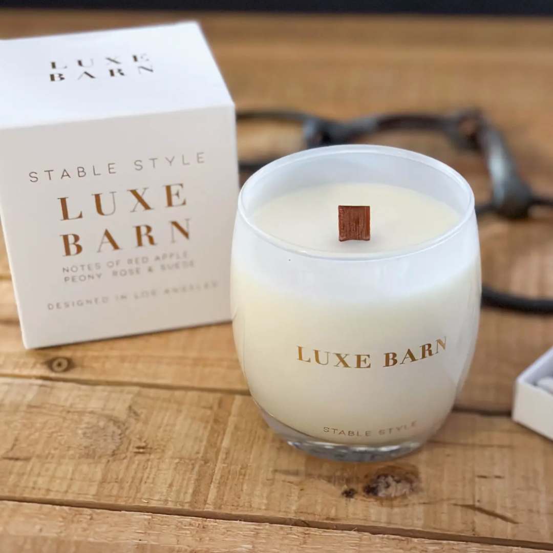 Stable Style Luxe Barn glass candle with wood wick displayed on a wooden table.