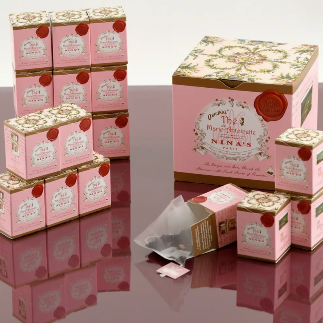 Luxurious Nina's Paris Marie Antoinette Tea in a beautifully crafted gift box. The set includes 18 petite pink boxes, each with a single tea bag, highlighting the exquisite Ceylon tea blend with rose petals, apple essence, and rose from Versailles. Perfectly presented for a royal tea experience.