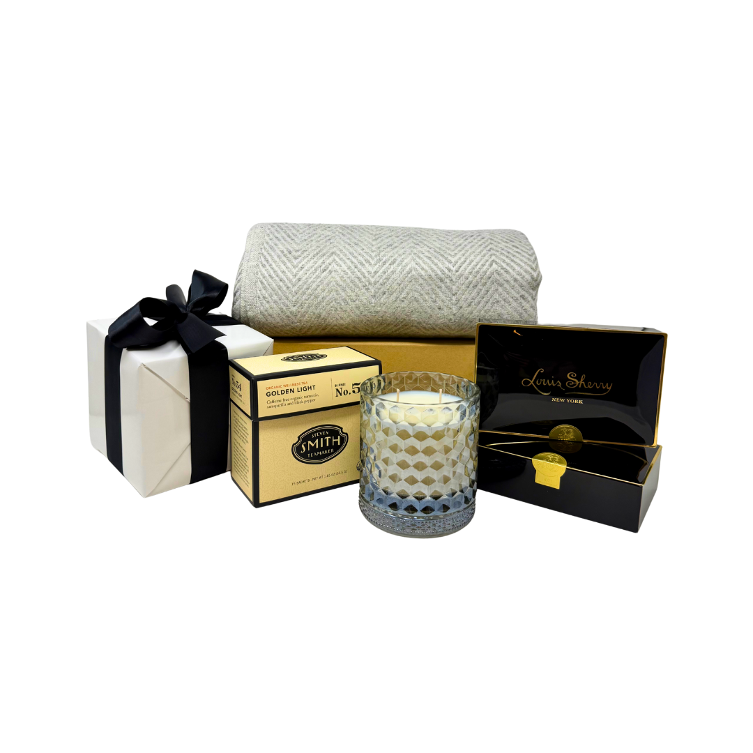 Gift set with a candle, box, and folded blanket on a white background