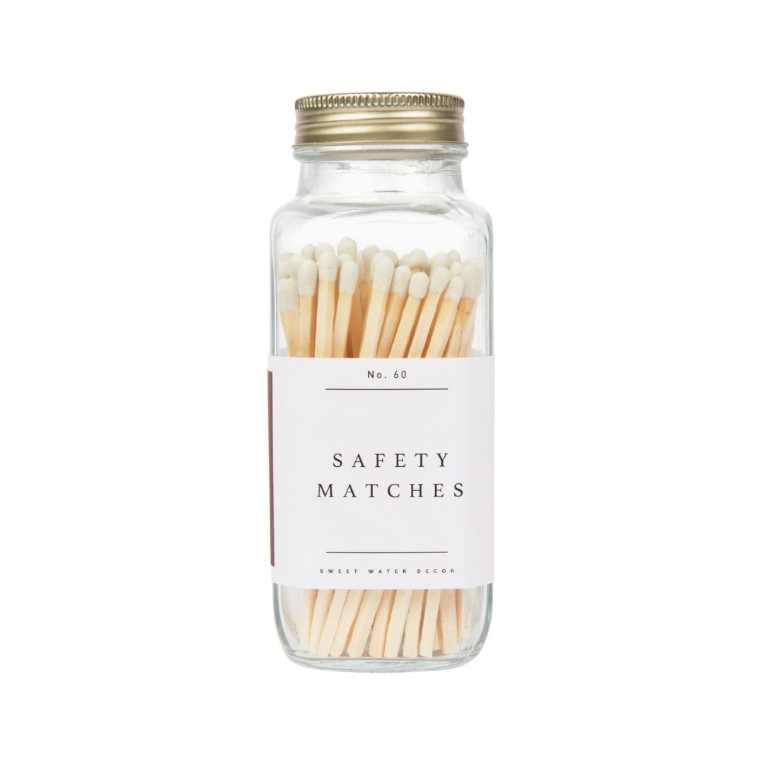 Matches In Glass Bottle With Gold Lid. The matches are wooden, the tips are white and the background is white.