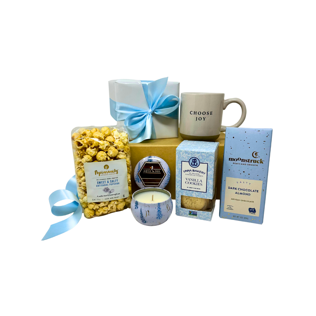 Gift basket with popcorn, coffee mug, candles, and chocolate on a white background