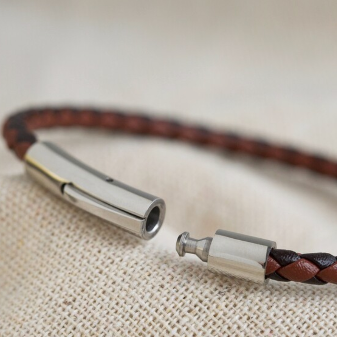 Close up view of the silver metal clasp of a man's brown leather slim braid bracelet.