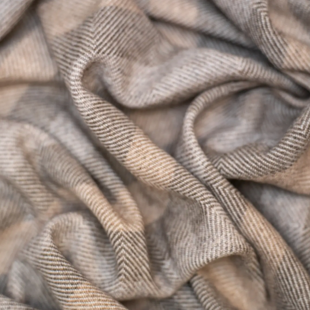Close-up of textured cashmere fabric with striped pattern in neutral beige tones.