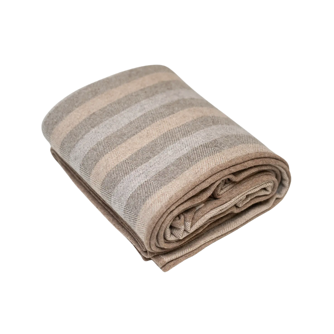 Folded cashmere blanket with neutral striped pattern on a white background.