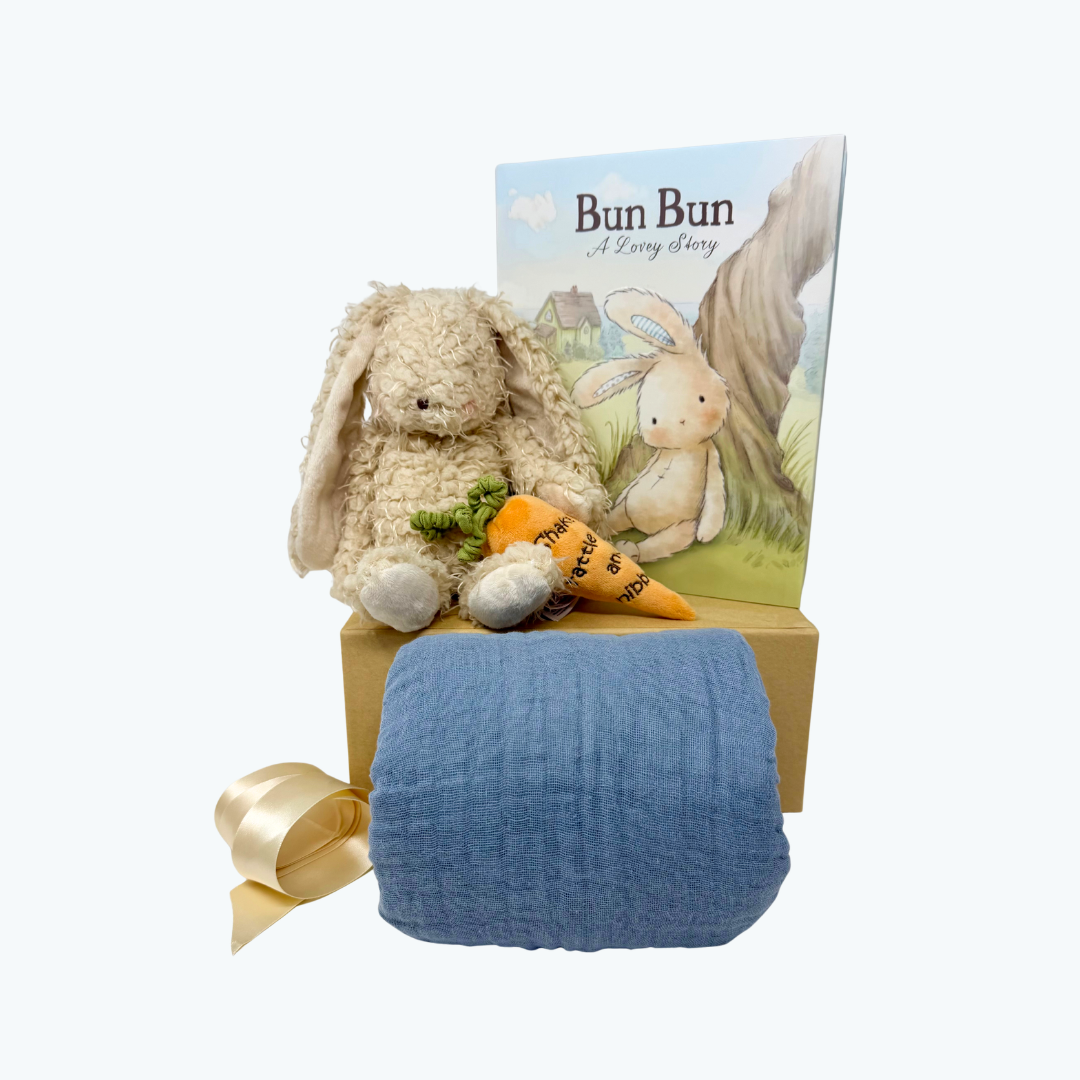 Baby gift set with plush bunny, book, and blue blanket on a white background.
