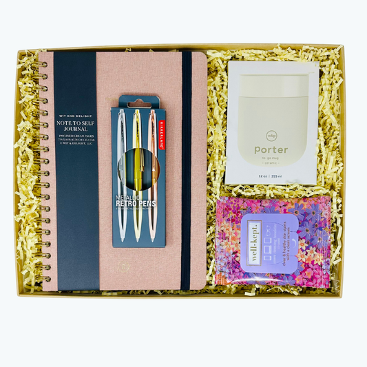 Gift set with a linen journal, pen set, W&P tumbler, Well-Kept screen wipes and other items in a box with yellow crinkle paper.