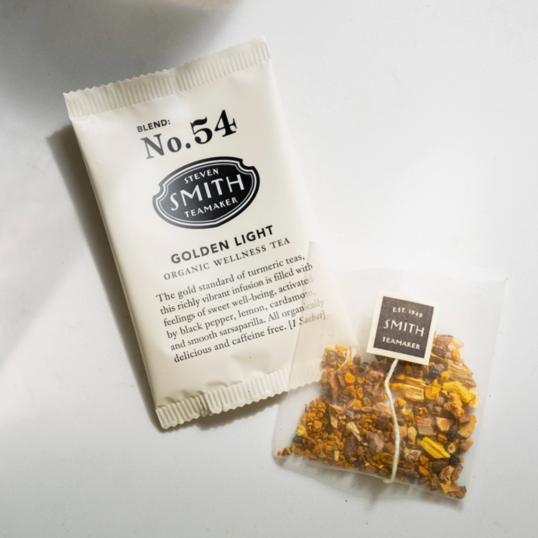 An open box of Organic Wellness Tea-Golden Light, with the tea bags arranged inside, revealing their delicate, golden-colored wrappers and the tea’s calming, herbal blend.