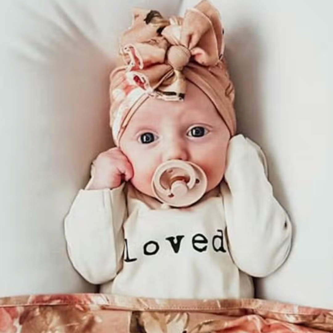 Organic cotton bodysuit for babies, showcasing 'Loved' text in black on a cream base.