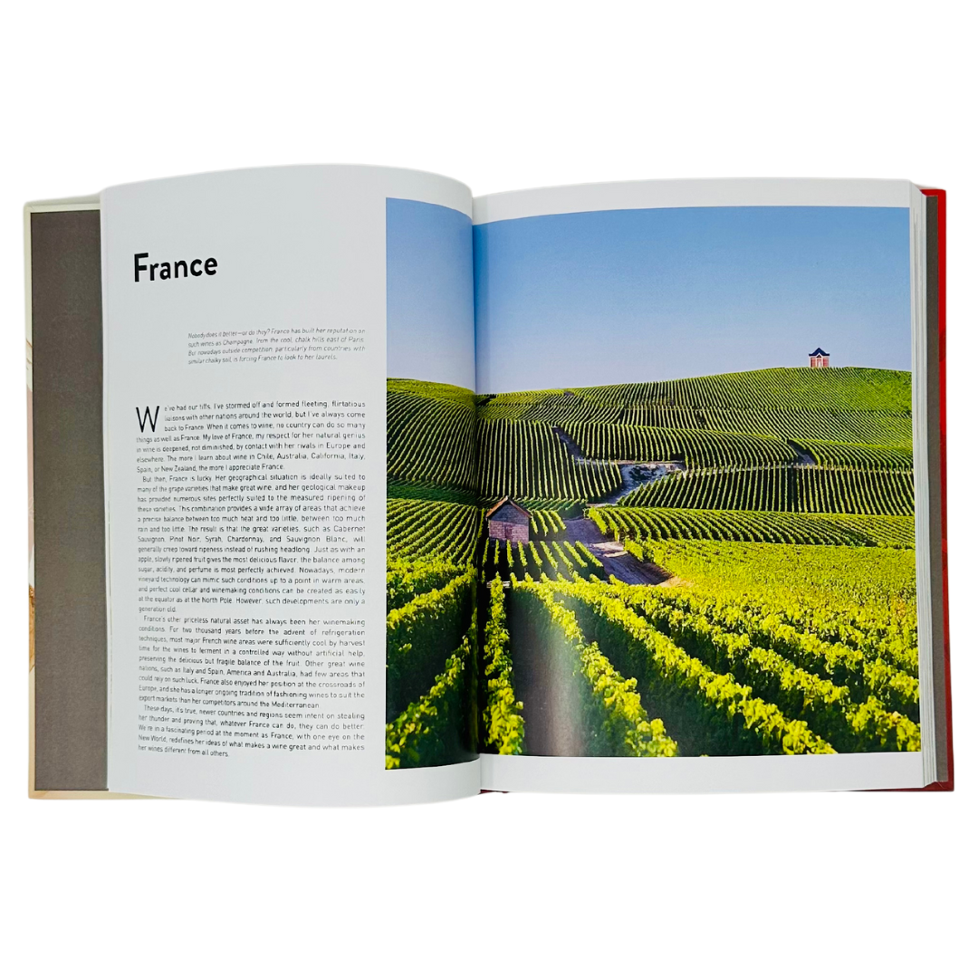 Oz Clarke's book: Hardcover open to a scenic French vineyard, vines stretching under blue skies, evoking elegance and terroir.