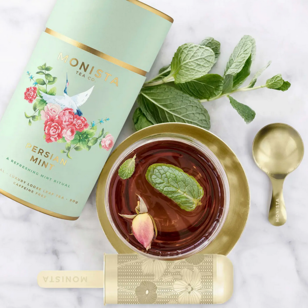 Close-up of the Monista Tea Co. Organic Persian Mint Tea canister, showcasing its elegant design, alongside the gold tea stick infuser, highlighting the premium quality of the gift set.