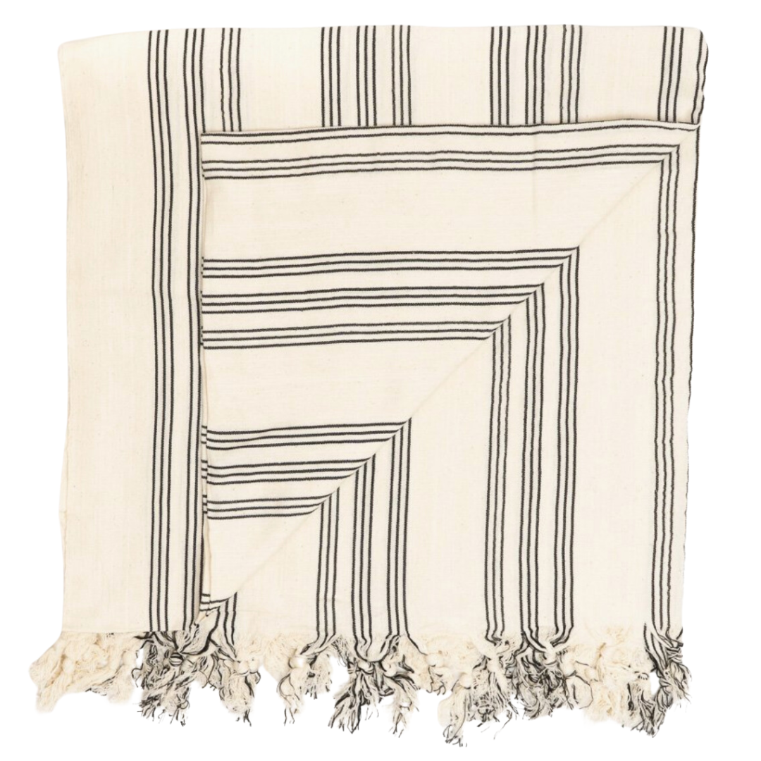 Peshtemal Cotton Towel: A versatile 38'' x 70'' cotton towel, perfect for various uses including as a bath towel, beach blanket, picnic cover, or yoga mat. Featuring a thin, no-terry design for quick drying and exceptional absorbency, this elegant towel is crafted in Turkey for practicality and style. The color is cream with black stripes.