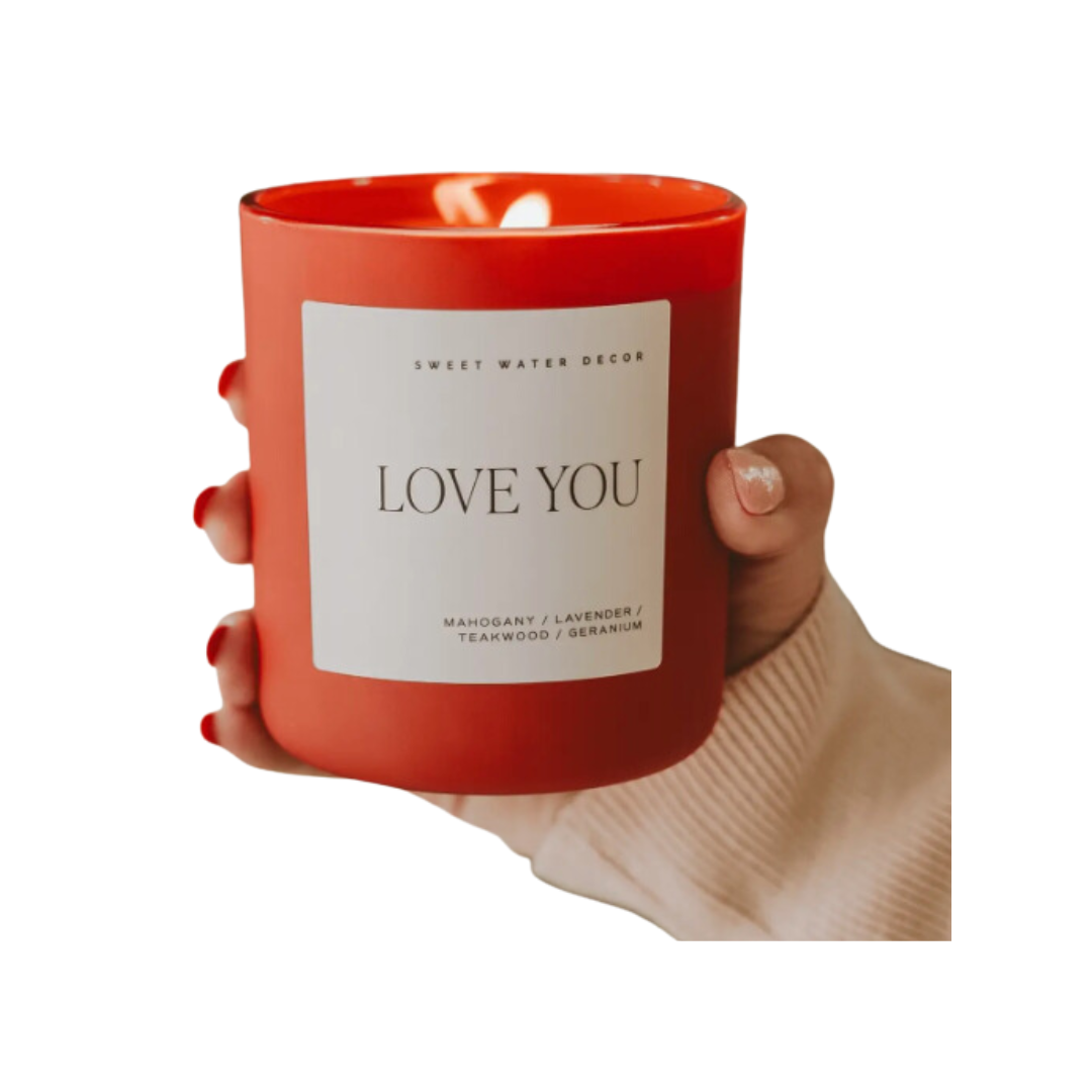 Red "LOVE YOU" candle with Driftwood and Mahogany scent, featuring notes of lavender, geranium, and teakwood for a cozy, intimate atmosphere.