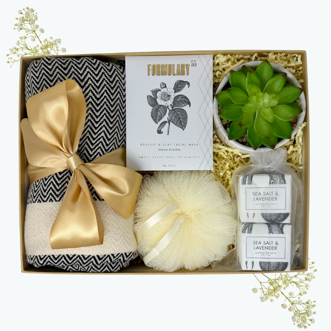 Gift set with bath items including a towel, candle, and sea salt and lavender product in a box.