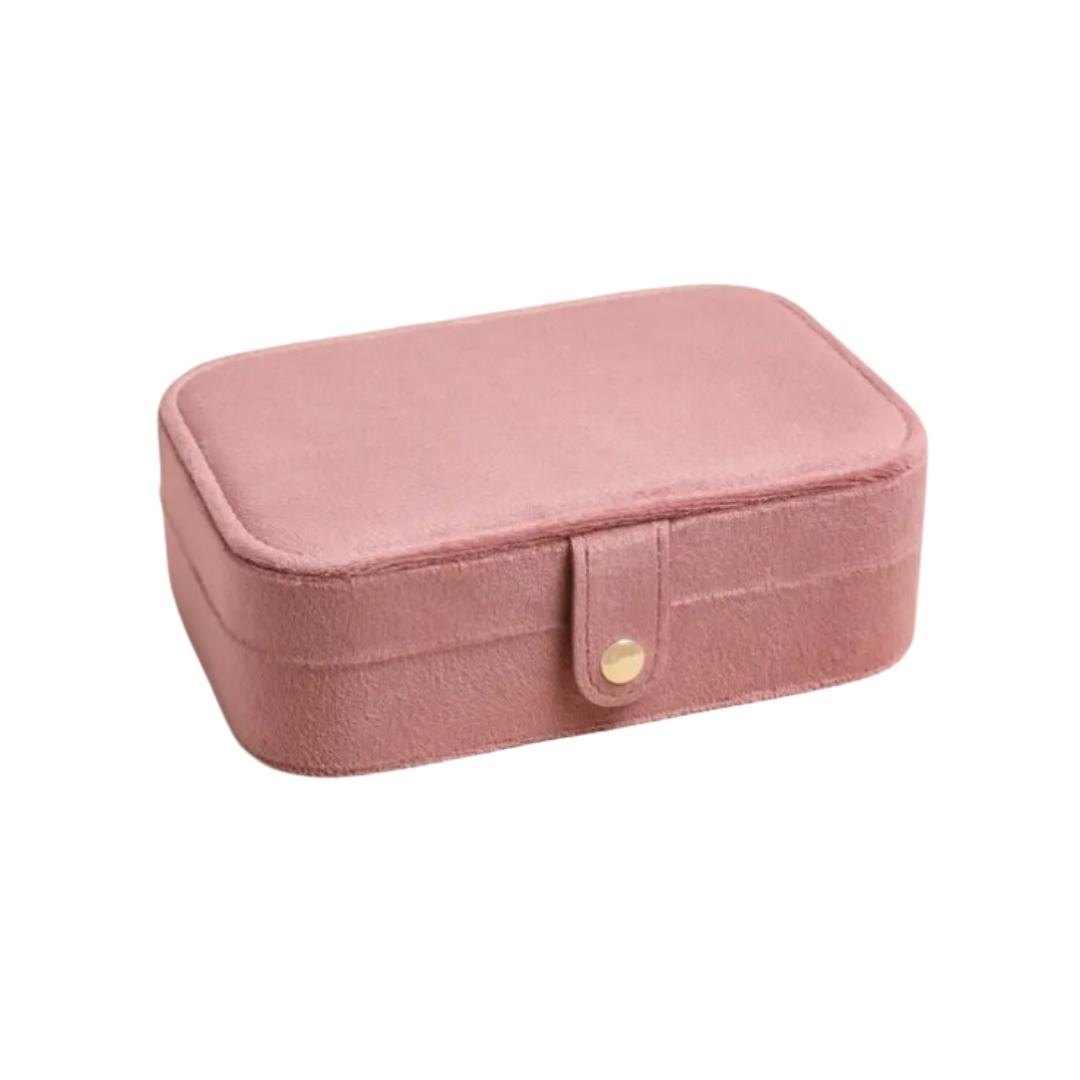 Rose pink velvet travel jewelry box with a rectangular design, curved edges, and a popper closure, featuring compartments for rings, studs, and necklaces.