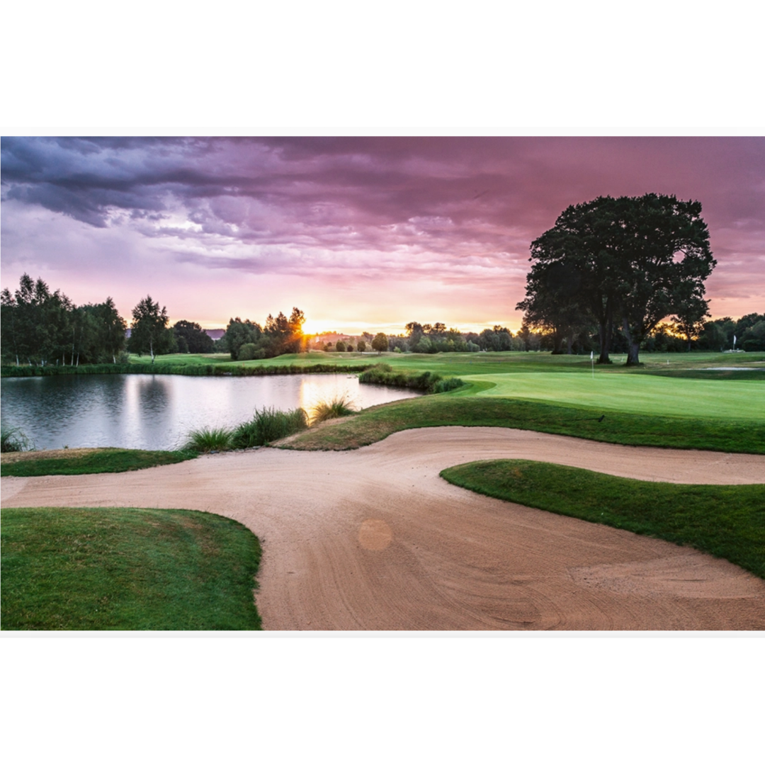 Golf course with a sand trap and lake at sunset
