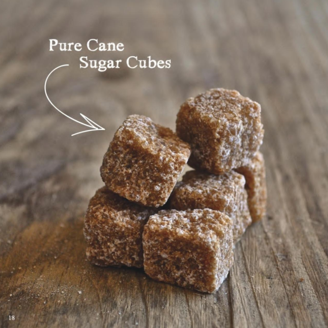 Simple and approachable cocktail recipe book for entertaining and hosting including recipes using pure cane sugar cubes. Six brown pure cane sugar cubes are stacked on a wooden table.