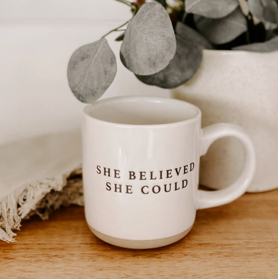 Hand-crafted 14oz stoneware mug with a natural bottom and a unique speckled finish, displaying the motivational text 'She Believed She Could' in classic black lettering.