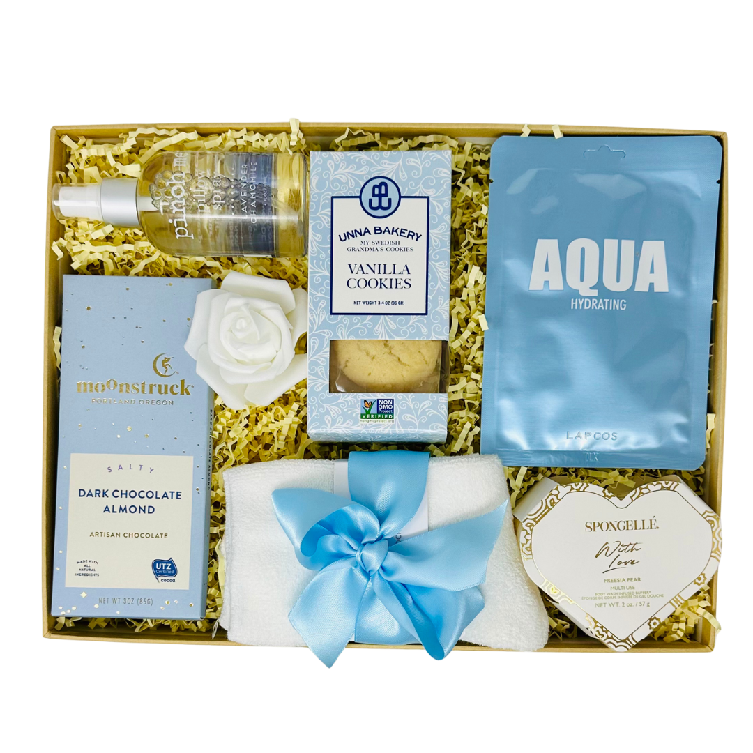 Gift set with products including a pillow spray, cookies, and other items arranged in a box.