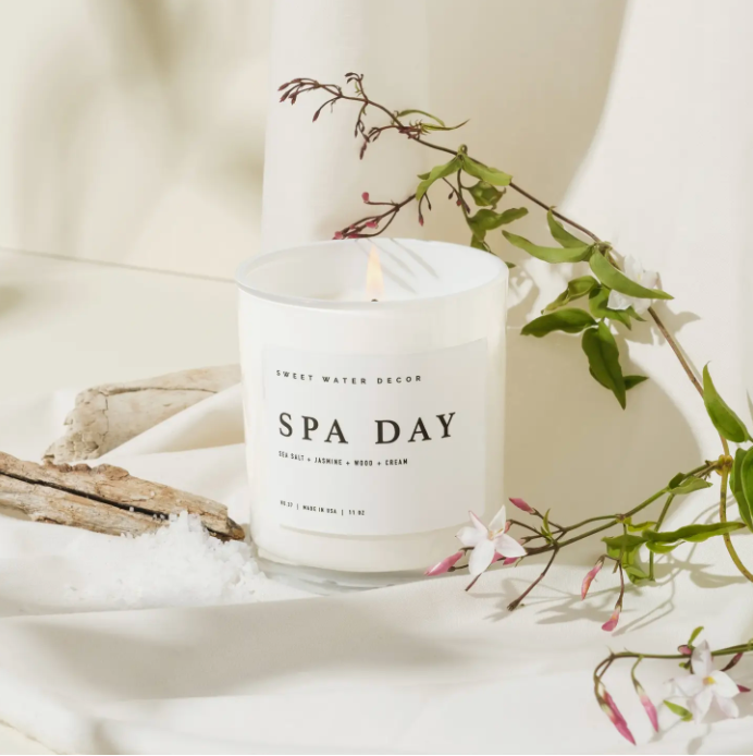 Luxury 'Spa Day' Candle: An elegant 11oz soy candle in a white glass jar with a wooden lid, designed to create a serene environment. Infused with a blend of sea salt, jasmine, and woody notes, this candle offers a calming atmosphere and burns for over 50 hours. It features a cotton wick and soy-based wax, ensuring a non-toxic, vegan, and eco-friendly experience.