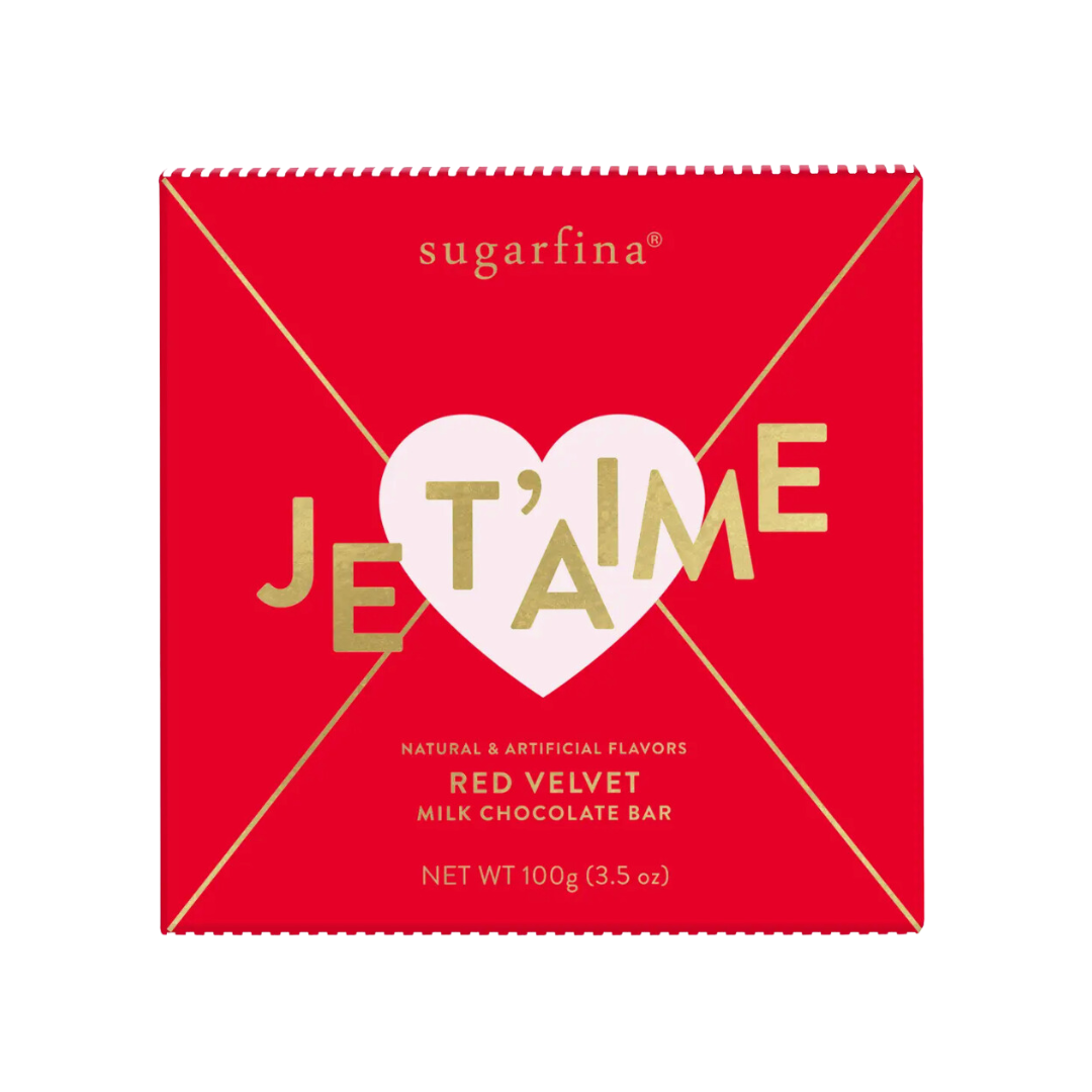 Close-up of Sugarfina's red velvet milk chocolate bar, featuring a decadent red velvet-flavored center, perfect for Valentine's Day gifts. The square package is vibrant red with a pink heart and the word Jet'aime in gold.