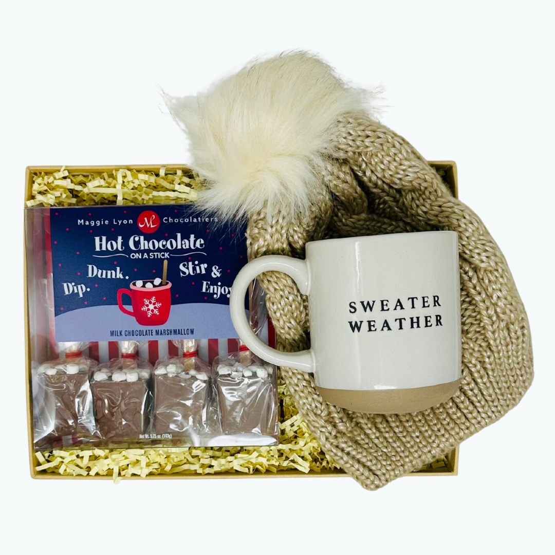 Gift set with 'Sweater Weather' mug, hot chocolate packets, and a knit hat in a box.