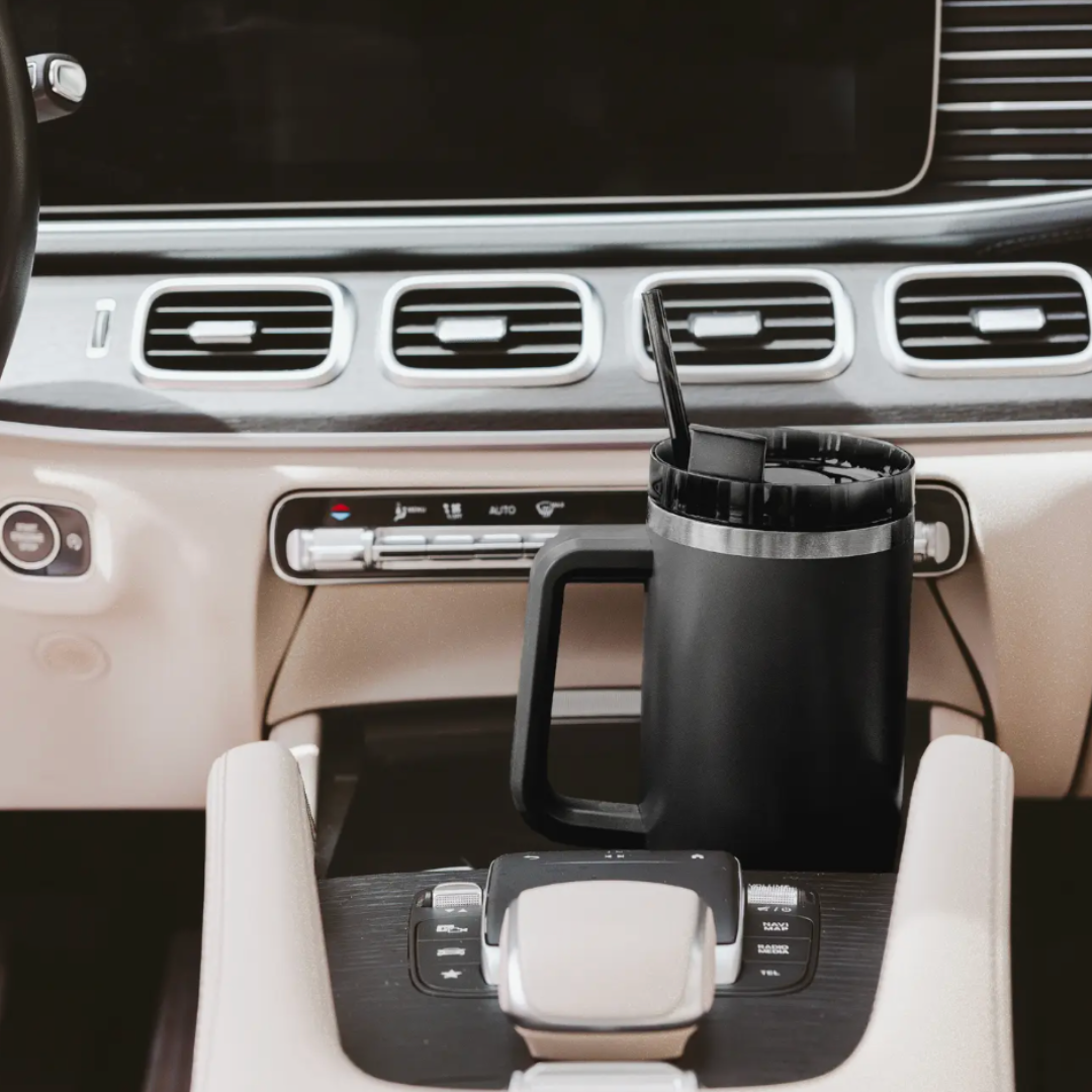 Black mug with a straw in a car cup holder.