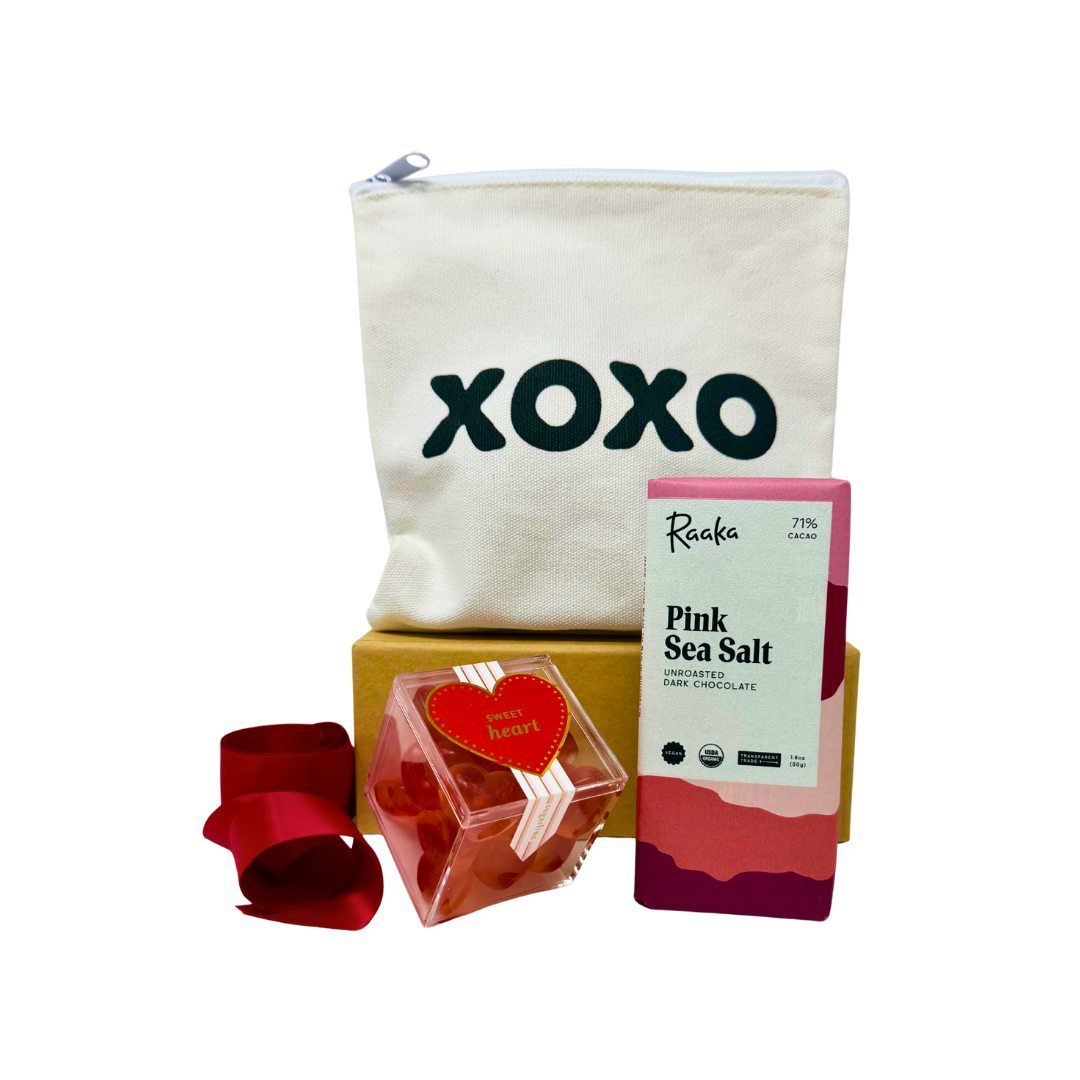 XOXO square zipper canvas pouch with pink sea salt chocolate bar, heart gummies in an acrylic box and red ribbon on a white background.