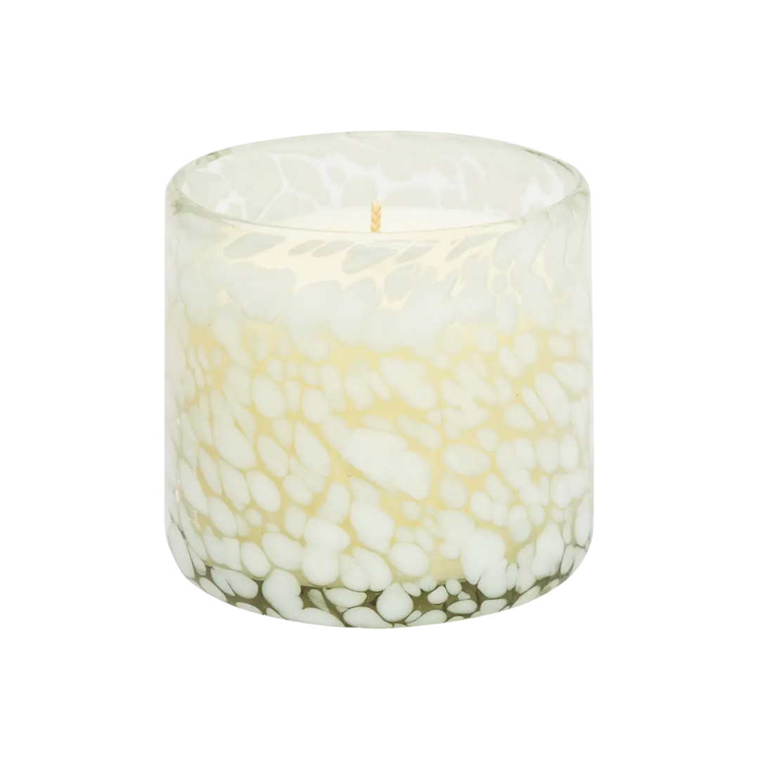 Candle in a glass container with pebble design on a white background.