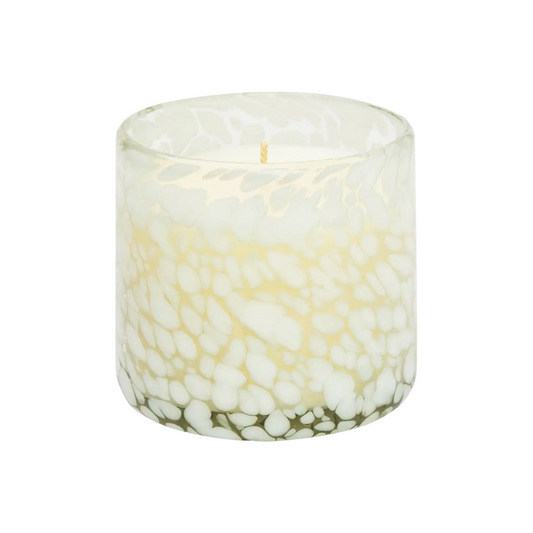 Candle in a glass container with pebble design on a white background.