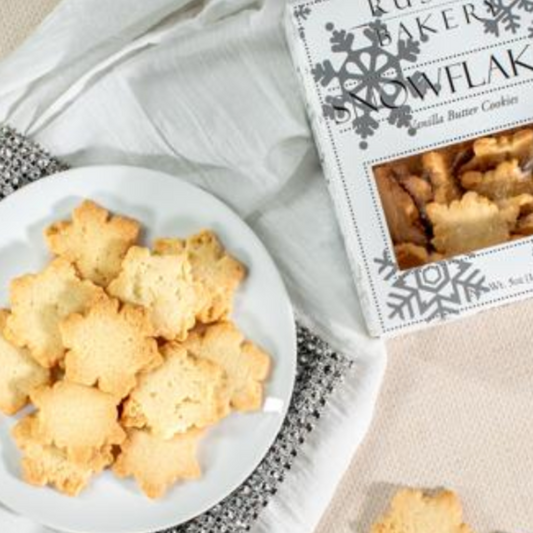 A beautifully arranged plate of Rustic Bakery's nostalgic cut-out snowflake cookies, featuring delicate butter cookies infused with Madagascar vanilla. The cookies are elegantly shaped and dusted with powdered sugar, capturing the charm of holiday traditions, ideal for gifting or sharing at festive gatherings.