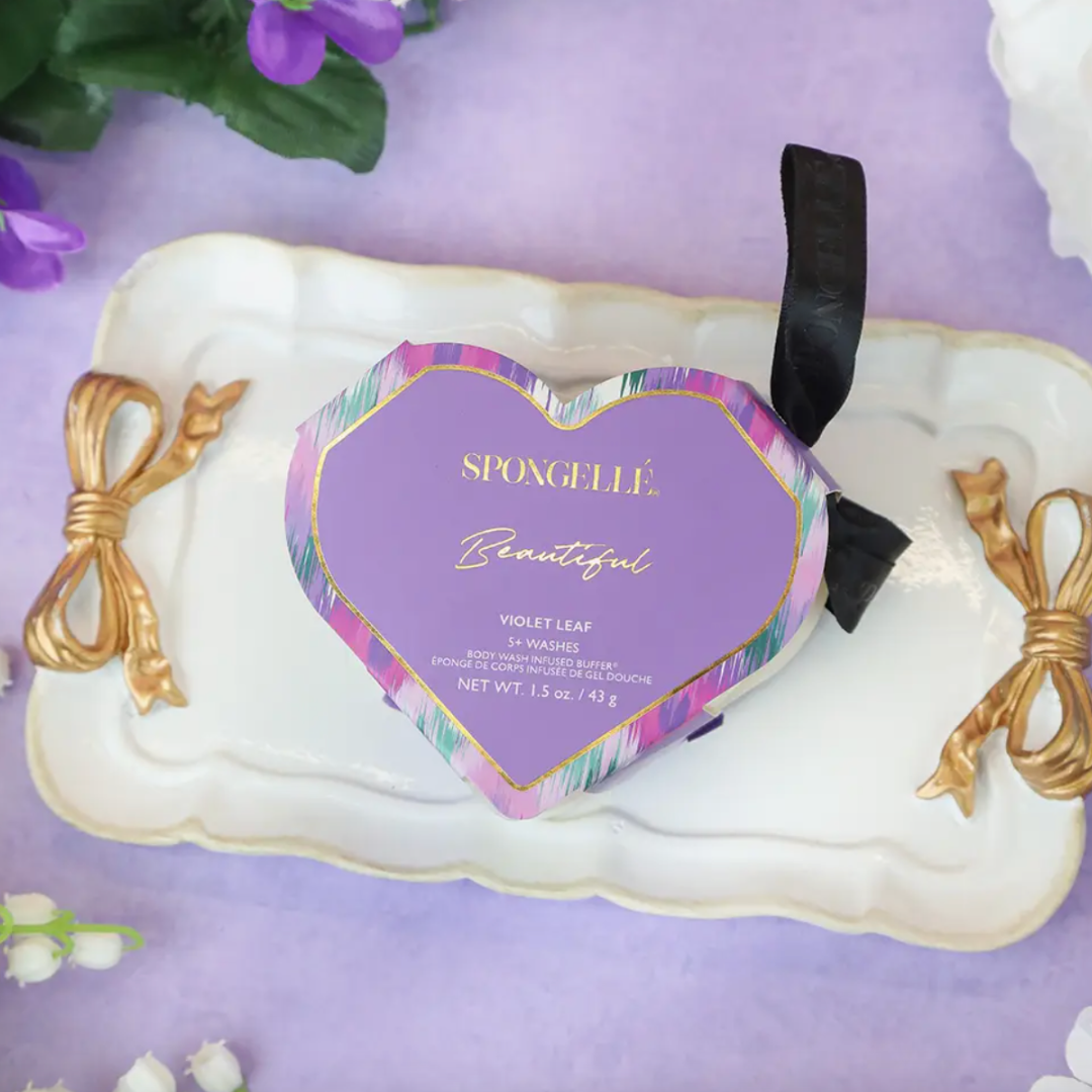 A collection of Spongellé’s heart-shaped body wash buffers, enriched with skin-softening extracts. The buffers are shown with a luxurious texture, designed to cleanse, exfoliate, massage, and nourish the skin. They are depicted in a way that highlights their elegant shape and multi-functional skincare benefits.