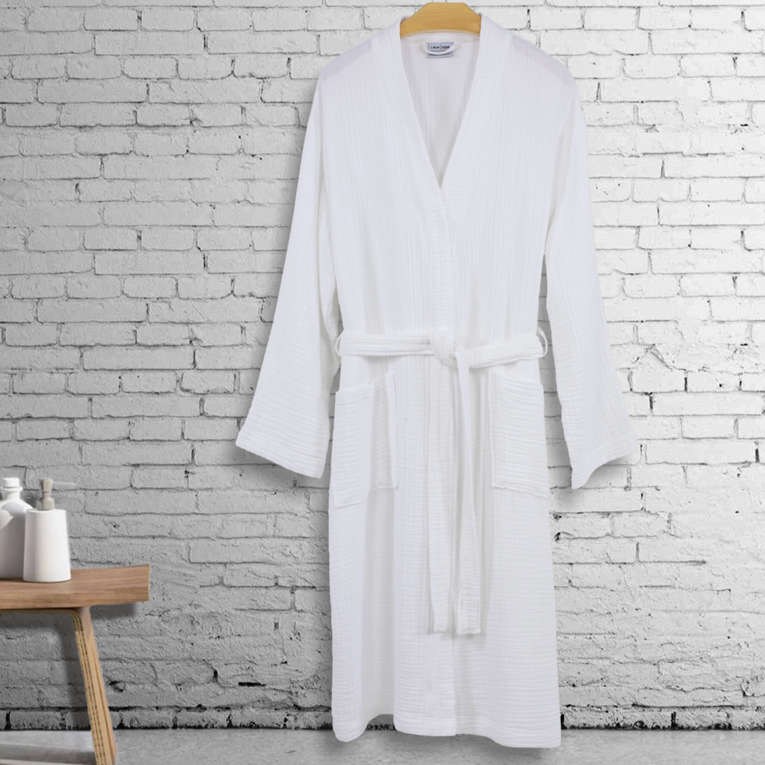 A beautifully hung white spa robe showcasing its gauzy texture and soft fabric. Perfect for lounging or post-shower wear, this robe includes practical side pockets for essentials.