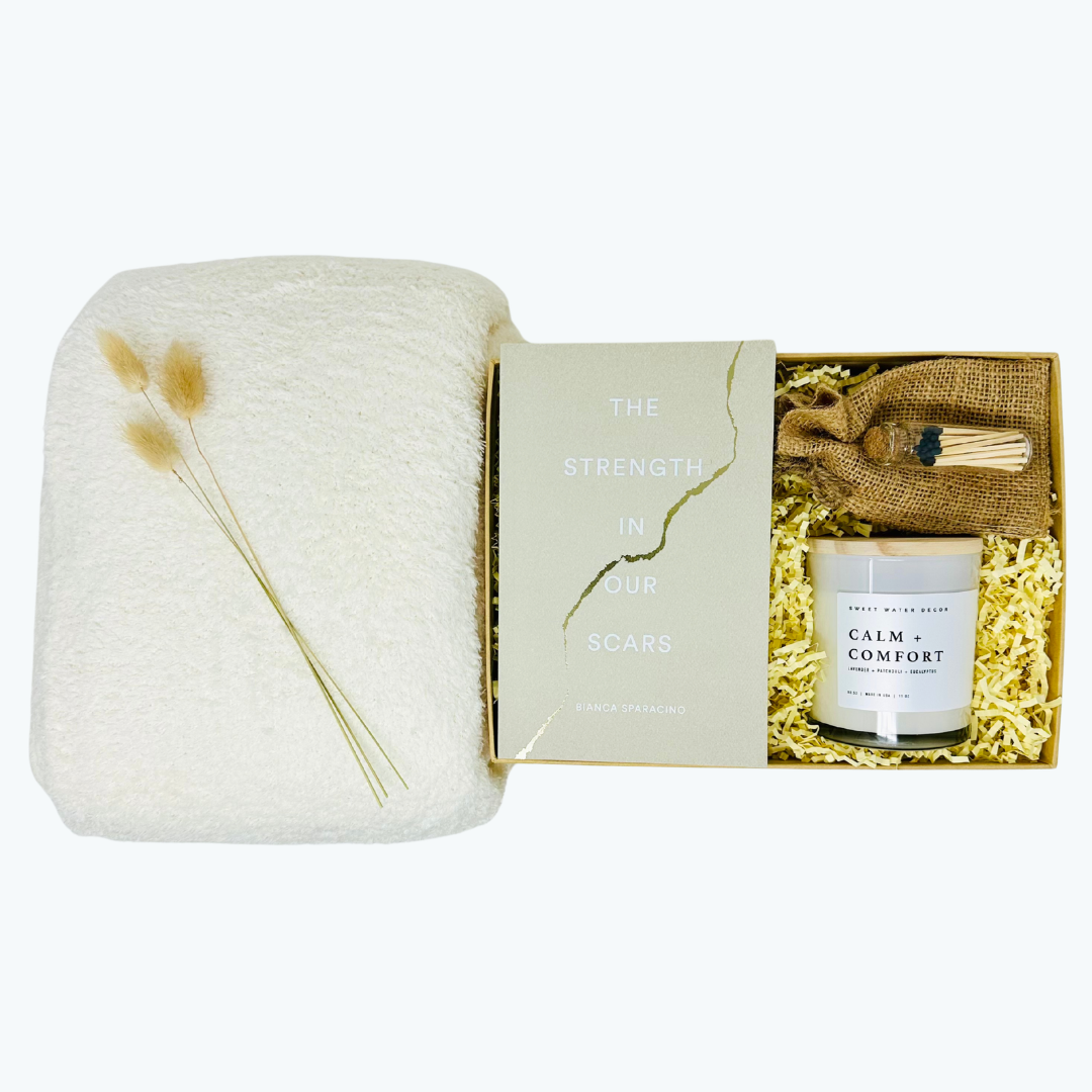 Gift set with a candle, soft blanket, candle, matches, book and decorative elements in a box on a white background.