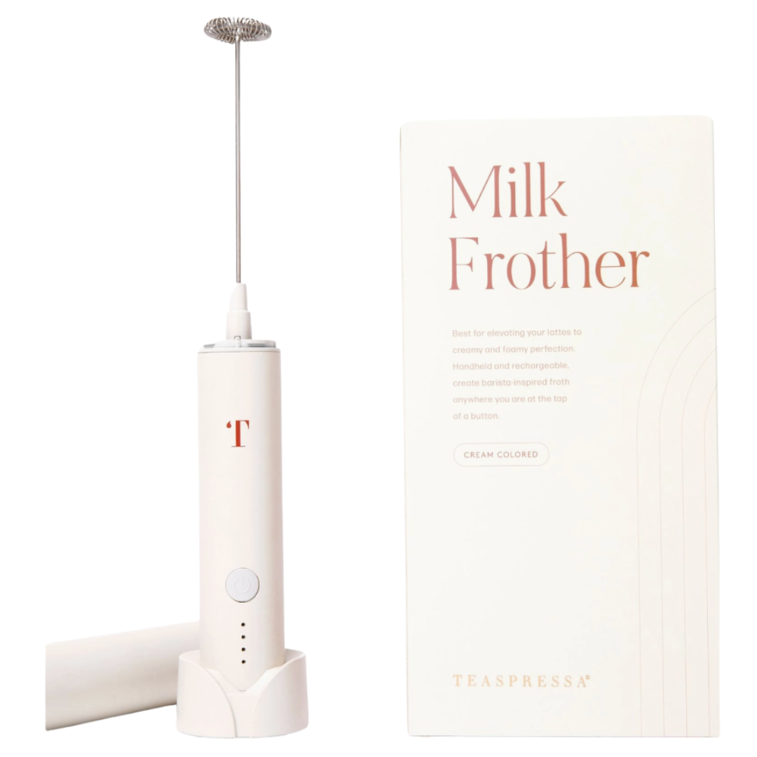 A cream-colored Teaspressa milk frother standing upright next to its white packaging box on a clean white background.