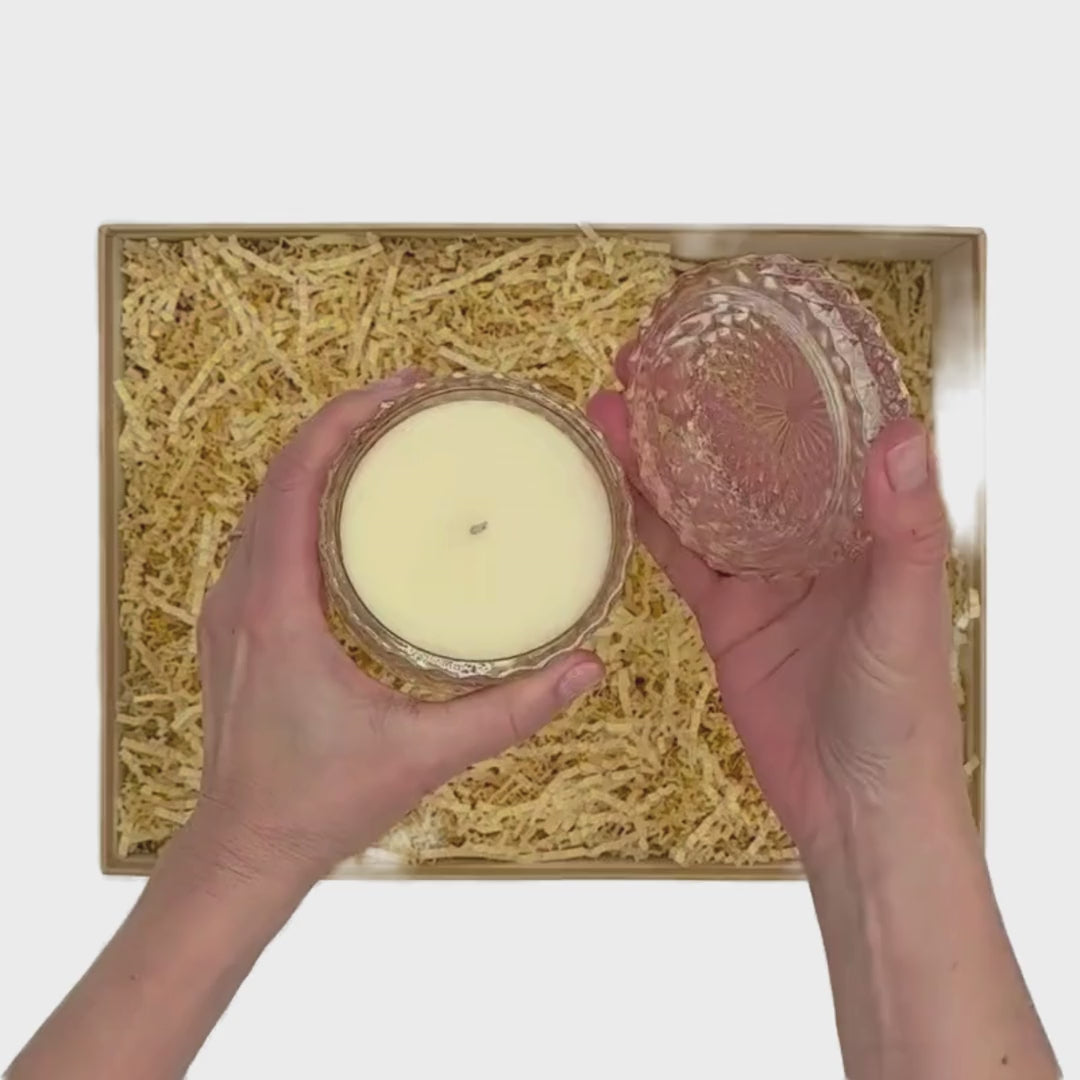 Video of two hands curating the Me To You Box gift box called Send Happiness. The gift has a beautifully wrapped rose vanilla cut glass candle with large pink bow, a pink happiness guided journal, an infused body buffer in peony, cozy white socks and jar of lip balm by Sara Happ.