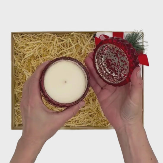 Video of Me To You Box's curated gift box called Happy Holidays.  This beautifully wrapped holiday gift box contains a red cut glass candle with glass lid, a bag of peppermint bark sheets, glass jar of five inch matches to go with the candle, a felt beaded snowflake ornament and a kitchen towel with colorful winter cottages on it.