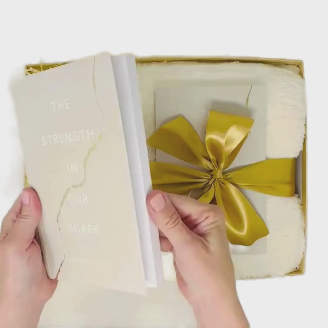 Video of With Sympathy Gift Box being curated in a box with gold satin ribbon and white gloss wrapping paper.