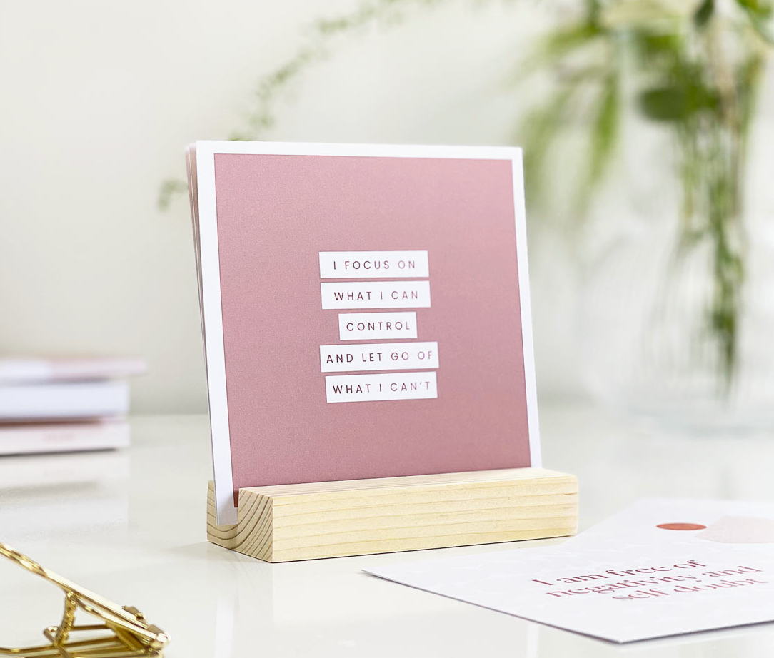 A collection of motivational affirmation cards nestled in a rustic wooden holder.
