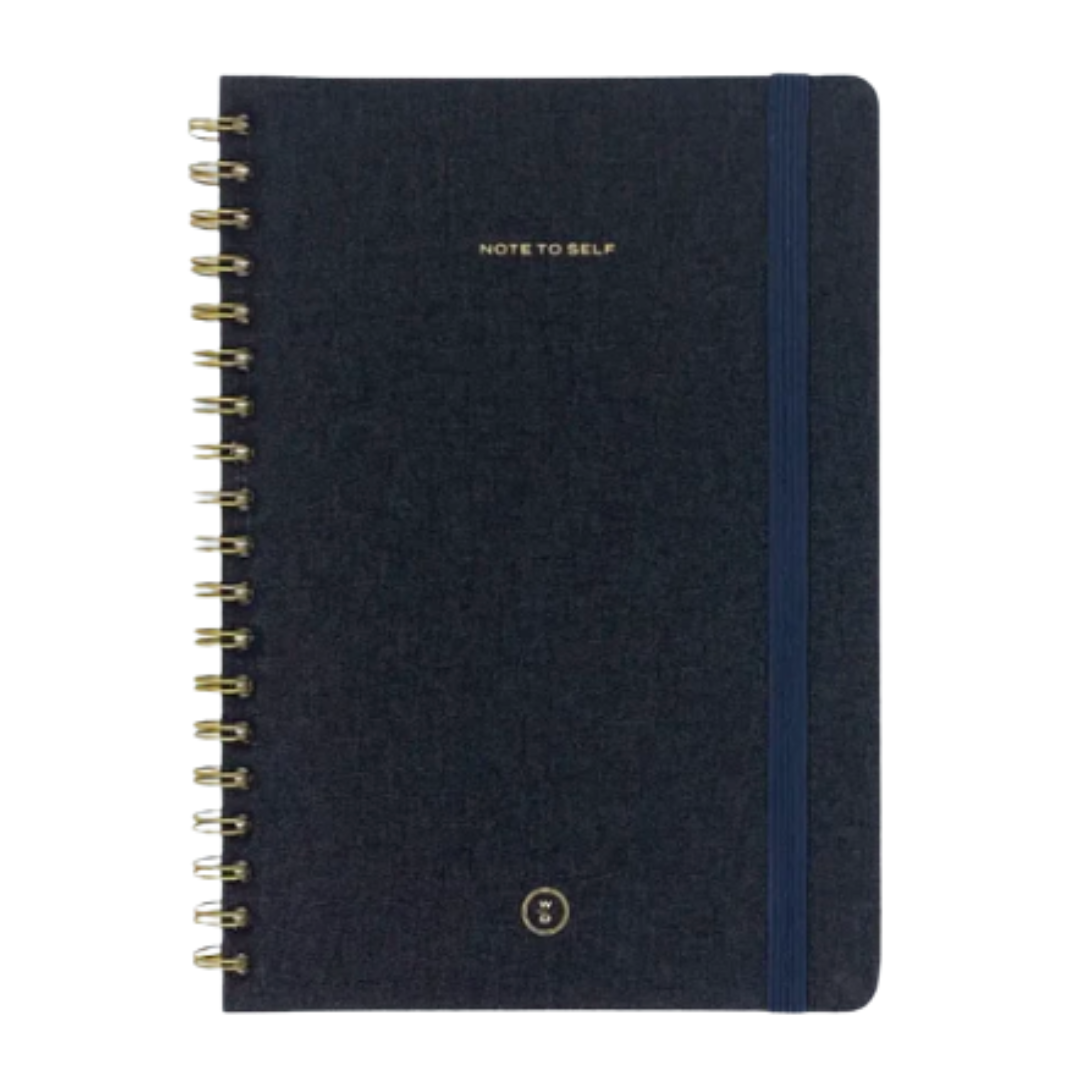 Witt & Delight charcoal linen covered spiral bound journal with lined pages and an elastic closure.