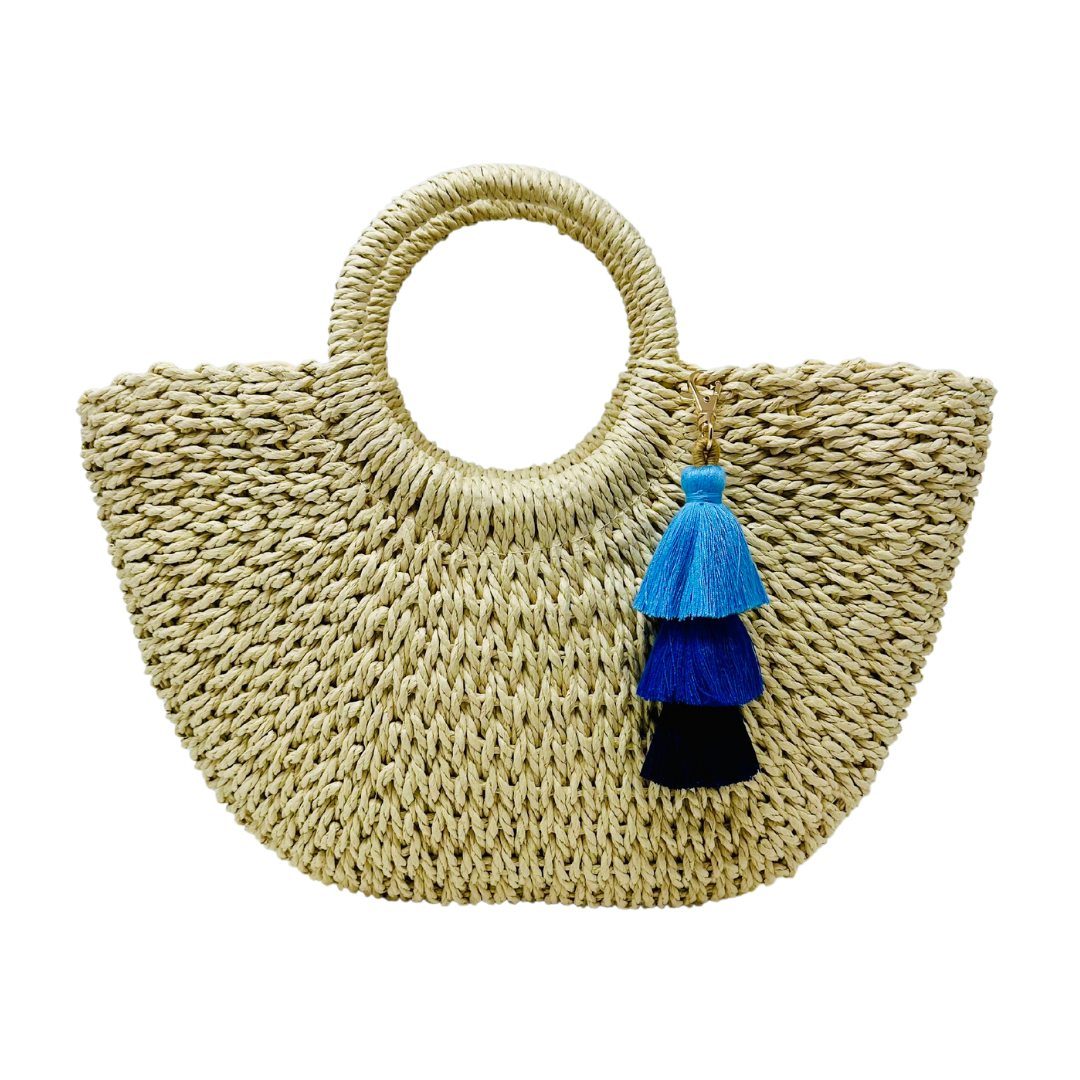 Fashionable straw bag with handles, drawstring pouch, and stylish blue ombre tassel detail.