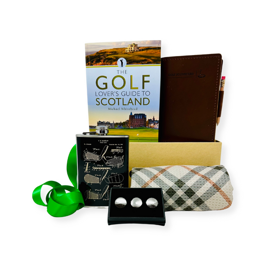 A curated gift box by Me To You Box named 'In The Zone'. It includes a leather score book with pencil, a plaid towel, golf ball markers, a flask, and a book on golf in Scotland.